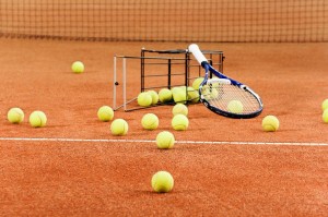 Tennis balls scattered from basket on court